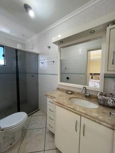 a bathroom with a toilet and a sink and a shower at Apto no Centro de Guaíra com ar condicionado na sala e quarto in Guaíra