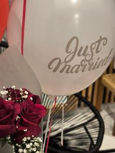 a bouquet of red roses and a balloon with the words just married at Imarkellis Santorini Cave House with yard in Pyrgos +25 photos