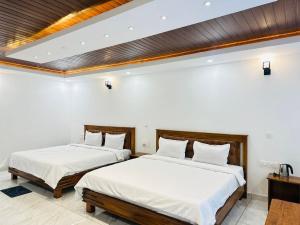 two beds in a room with white walls at Mistora Estate Villa in Suntikoppa