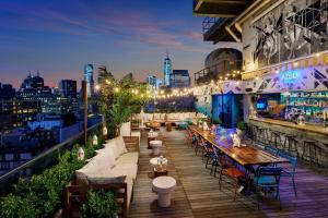 eine Dachterrassenbar mit Tischen und Stühlen auf einem Gebäude in der Unterkunft Hotel Hugo in New York