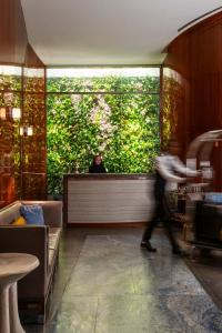 Eine Person geht durch ein Restaurant mit einer grünen Wand in der Unterkunft Hotel Hugo in New York