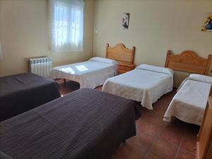 a room with three beds and a window at Casa Detrés in Cogollos de Guadix