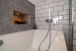 a white bath tub with a shower in a bathroom at Garden View Apartment in Salcombe +36 photos