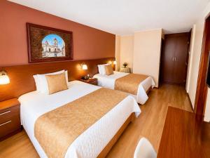 a hotel room with two beds and a table at Hotel Endamo in Latacunga