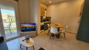 a living room with a table and a kitchen with a tv at Estia Chios Apartments B6 in Chios