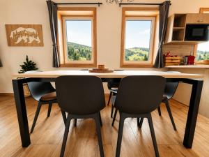 a dining room table with four chairs and two windows at Chalupa pod Špičákem in Smržovka