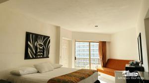 a bedroom with a bed and a couch and a window at Condominios Torre Continental Ixtapa in Ixtapa