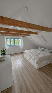 a white bedroom with a bed and a wooden floor at Pod Borovicí Broumy in Broumy
