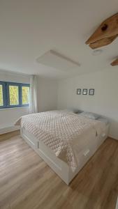 a white bedroom with a bed in a room at Pod Borovicí Broumy in Broumy