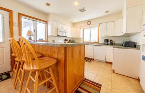 a kitchen with white cabinets and a bar with stools at Fun 'N Sun - Nags Head MP 16, 250 Ft to Beach Access, Pool, Pets OK, YR Flex Stays in Nags Head