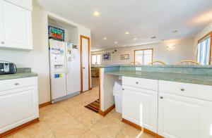 a kitchen with white cabinets and a refrigerator at Fun 'N Sun - Nags Head MP 16, 250 Ft to Beach Access, Pool, Pets OK, YR Flex Stays in Nags Head