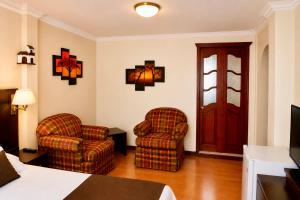 a hotel room with two chairs and a bed at Hotel Endamo in Latacunga
