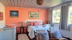 a bedroom with orange walls and a bed with chairs at Pousada Aconchego dos Puris in Resende