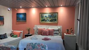 a bedroom with a large bed with pink walls at Pousada Aconchego dos Puris in Resende