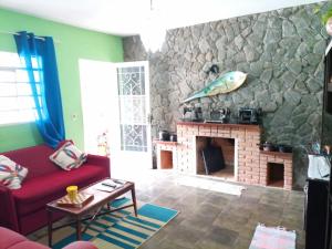 a living room with a red couch and a stone fireplace at Pousada Aconchego dos Puris in Resende
