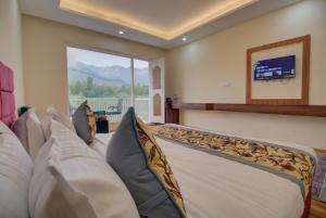 a bedroom with a bed with pillows and a tv at Royal Cliff Resort Pahalgam in Pahalgām