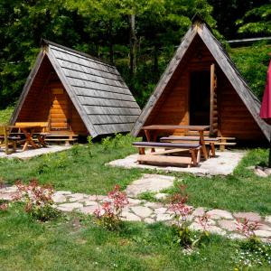 two wooden huts with a picnic table in the grass at Camp Vrbas in Rekavice