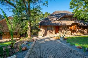 a stone house with a thatched roof at Kruger Park Lodge - Modern Unit 225B in Hazyview