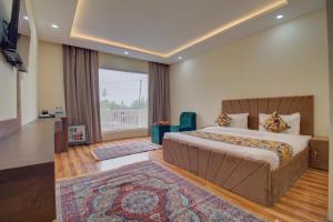 a bedroom with a large bed and a large window at Royal Cliff Resort Pahalgam in Pahalgām