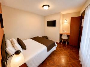 a hotel room with a bed and a television at Hotel Endamo in Latacunga