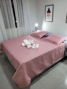 a bed with pink sheets and two towels on it at Diamond - Flat Bela Estância in São Lourenço +17 photos