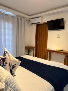 a bedroom with a bed with a tv on the wall at Pousada Banzay in Paraty