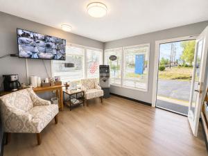 a living room with two chairs and a desk and windows at Royal Gateway Motel in Bend