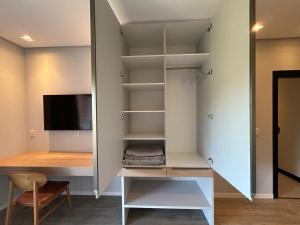a room with a closet with a tv and a desk at Suítes Bela Vista in Pomerode