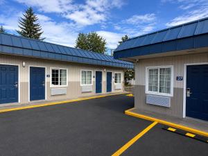 a row of garages with blue doors in a parking lot at Royal Gateway Motel in Bend