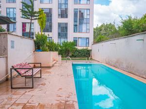 a swimming pool with a chair next to a building at Easy Stay Rongai Poolside 2BR near Karen WiFi and Netflix in Ongata Rongai 