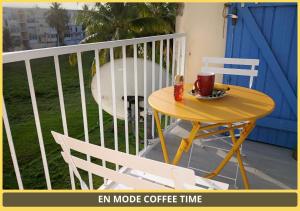 a table and chairs on a balcony with a cup of coffee at Chambre Carnaval Abymes Guadeloupe in Les Abymes