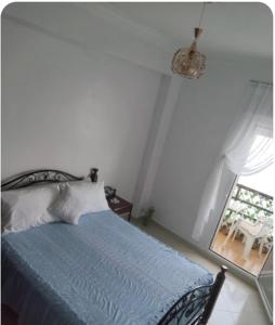 a bedroom with a blue bed and a window at Appartement vue mer à Fnideq in Fnidek