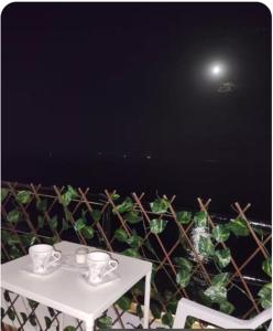 a white table with cups on it next to a plant at Appartement vue mer à Fnideq in Fnidek