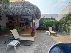 a resort with chairs and a pool and a straw hut at Villas Mercedes in Zihuatanejo