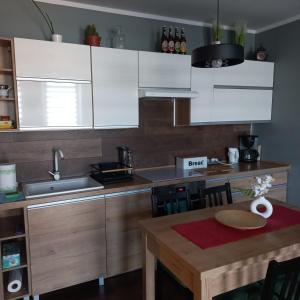 a kitchen with white cabinets and a wooden table at Apartament pod dębami in Trzcianka