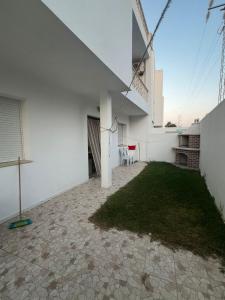 an empty patio with a lawn in a white building at Dyar Abdellatif in Kelibia