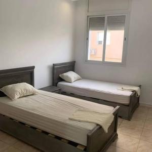 two beds in a room with a window at Dyar Abdellatif in Kelibia