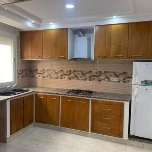 a kitchen with wooden cabinets and a white refrigerator at Dyar Abdellatif in Kelibia