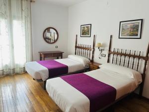 a room with two beds and a mirror at Hostal Pirineos Meliz in Bielsa