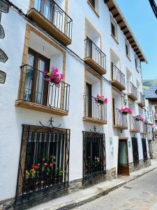 a white building with balconies and flowers on it at Hostal Pirineos Meliz in Bielsa