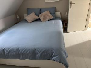 a blue bed with two pillows on top of it at La Dune Dorée Escapade Croteloise in Le Crotoy
