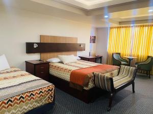 a hotel room with two beds and two chairs at Los Angeles Stay Inn in Quito