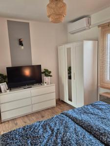 a bedroom with a tv on a dresser with a bed at Balatoni Horizont Vendégház in Balatonakarattya