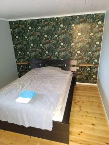 a bedroom with a bed with a floral wall at Cozy cabin near the river in Kangos