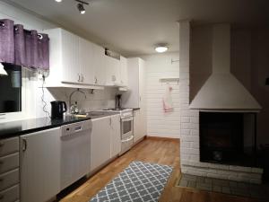 a kitchen with white cabinets and a fireplace at Cozy cabin near the river in Kangos +25 photos