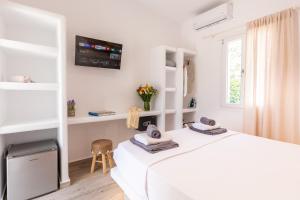 a white bedroom with a white bed and a window at Alexandra Suites - MYKONOS PORT in Mikonos