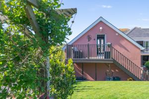a pink house with a balcony and a yard at Little Orchard House Self-catering Garden View apartment in Salcombe