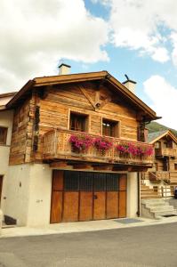 uma casa de madeira com uma varanda com flores em Armonia Livigno Appartamenti em Livigno