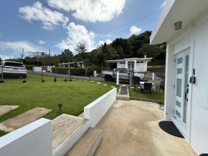 a white house with a yard with a lawn at Modern Private Stay in Fajardo, PR - NEAR FERRY - BEACHES - EL YUNQUE - BIO BAY in Fajardo