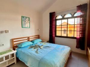 a bedroom with a bed with blue sheets and a window at fuerte blue in Costa Calma